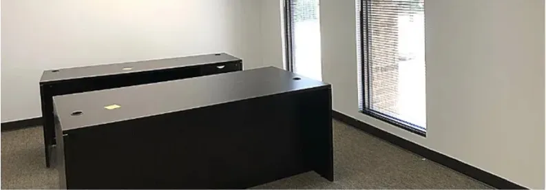 Corner office in Building A with two walls of windows and a desk set toward the glass.