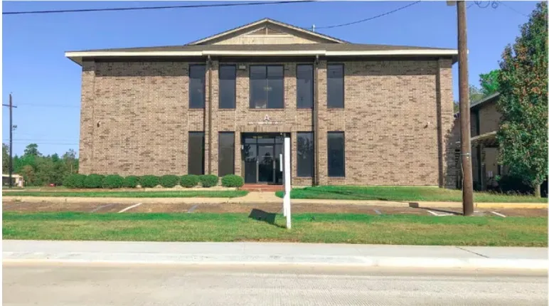 Building A at 100 Commercial Circle — two-storey brick office building seen from FM 2854, with surface parking in front.