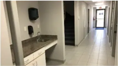 Kitchenette in Building A with a stainless sink, counter and a view down the corridor to the stairs.