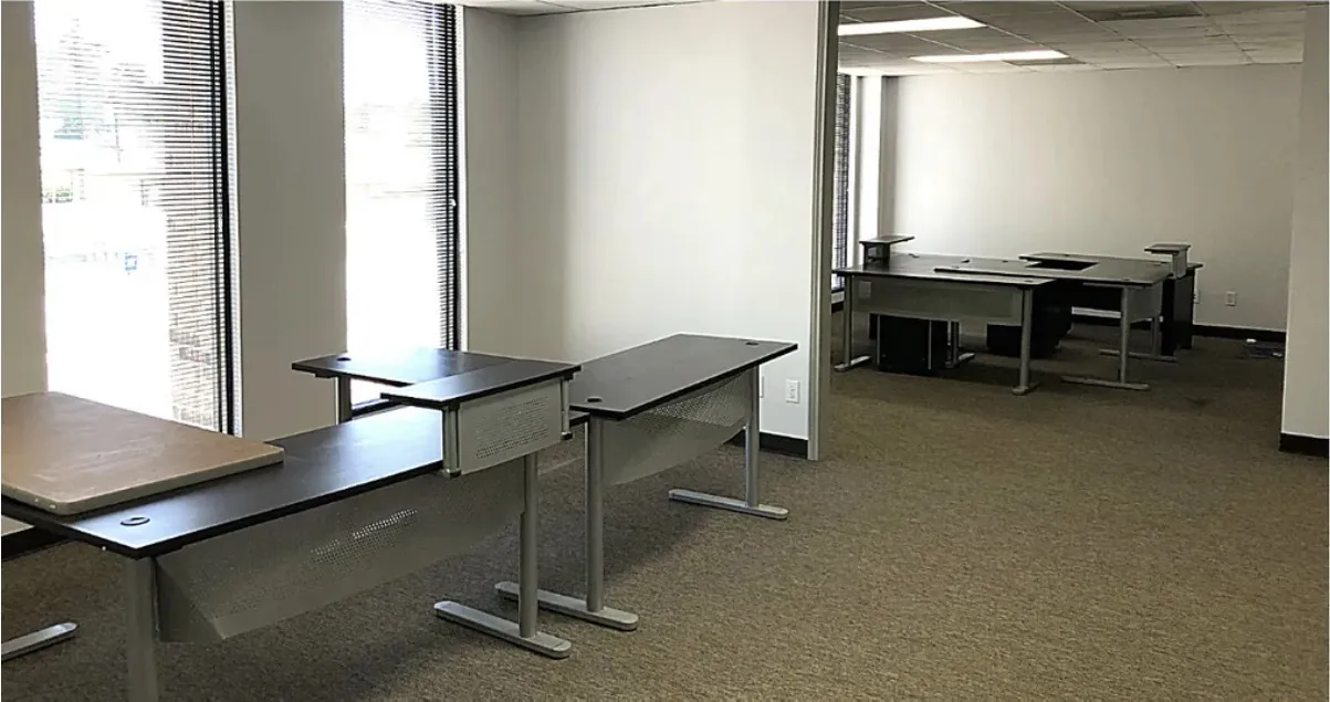 Open office in Building A with floor-to-ceiling windows on two walls and freestanding desks.