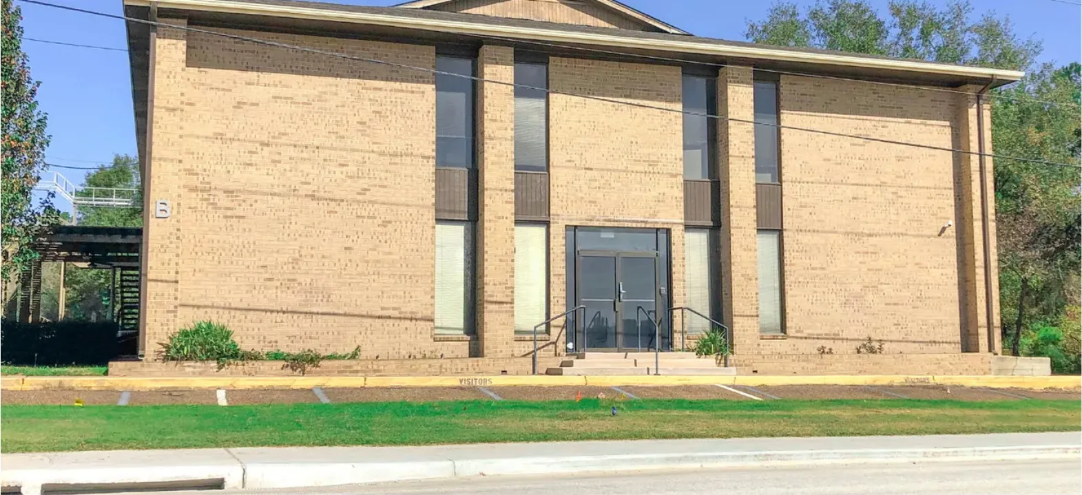 Building B at 100 Commercial Circle — two-storey brick office building with a glass double-door entrance and visitor parking.
