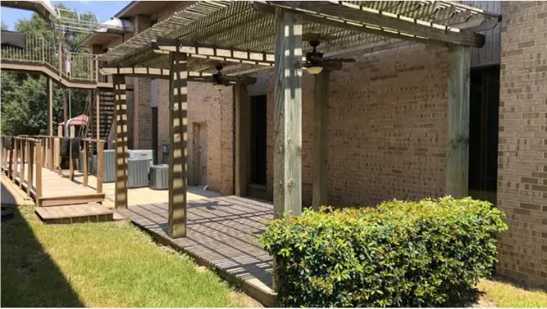 Covered pergola deck alongside Building B, with ceiling fans and a wood walkway.